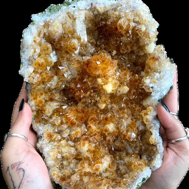 A citrine crystal cluster held in two hands.