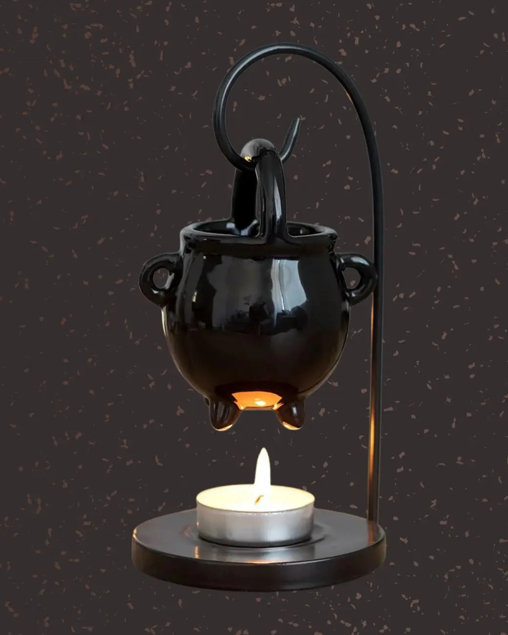 A black cast-iron cauldron oil burner with a lit tealight.