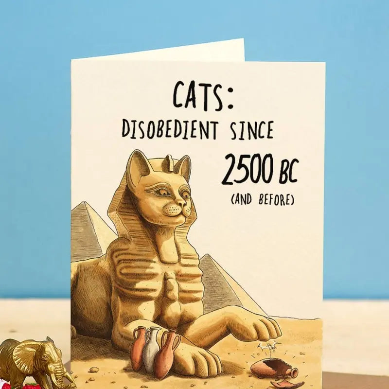A greeting card of a cat-headed sphinx knocking a pot off a ledge, captioned Cats: disobedient since 2500 BC.