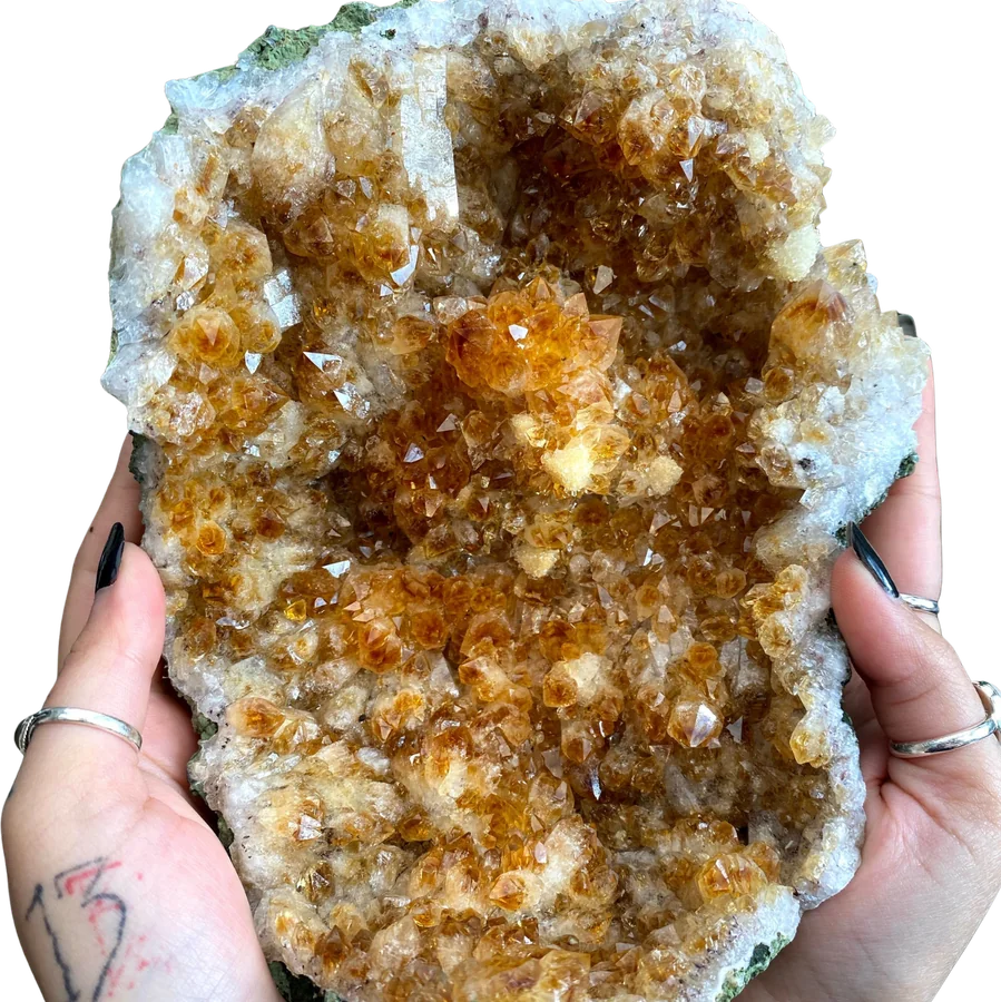 A citrine crystal cluster held in two hands.